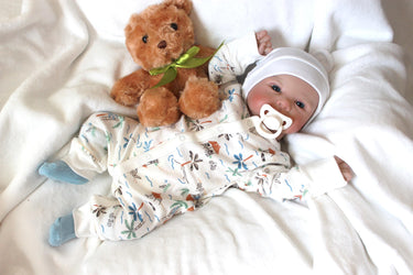 A baby doll positioned on a bed alongside a teddy bear, symbolizing innocence and the joy of playtime.